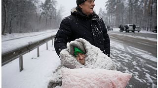 امرأة مسنة مغطاة بالثلج وهي تجلس على كرسي متحرك بعد إجلائها من إيربين، في ضواحي العاصمة كييف