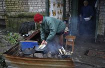Idosa ucraniana prepara uma refeição na rua