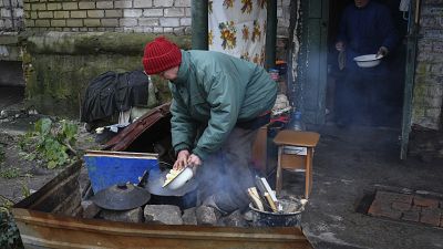 Idosa ucraniana prepara uma refeição na rua