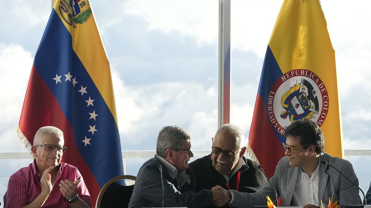 Miembros de las delegaciones del Gobierno colombia y de la guerrilla del ELN estrechan manos en la primera rueda de prensa tras primer encuentro en el hotel Humbold en Caracas