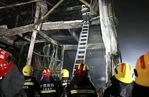 Rescuers use a ladder to climb into the remains of a fire at an industrial wholesaler in Anyang in central China's Henan province, 21 November 2022