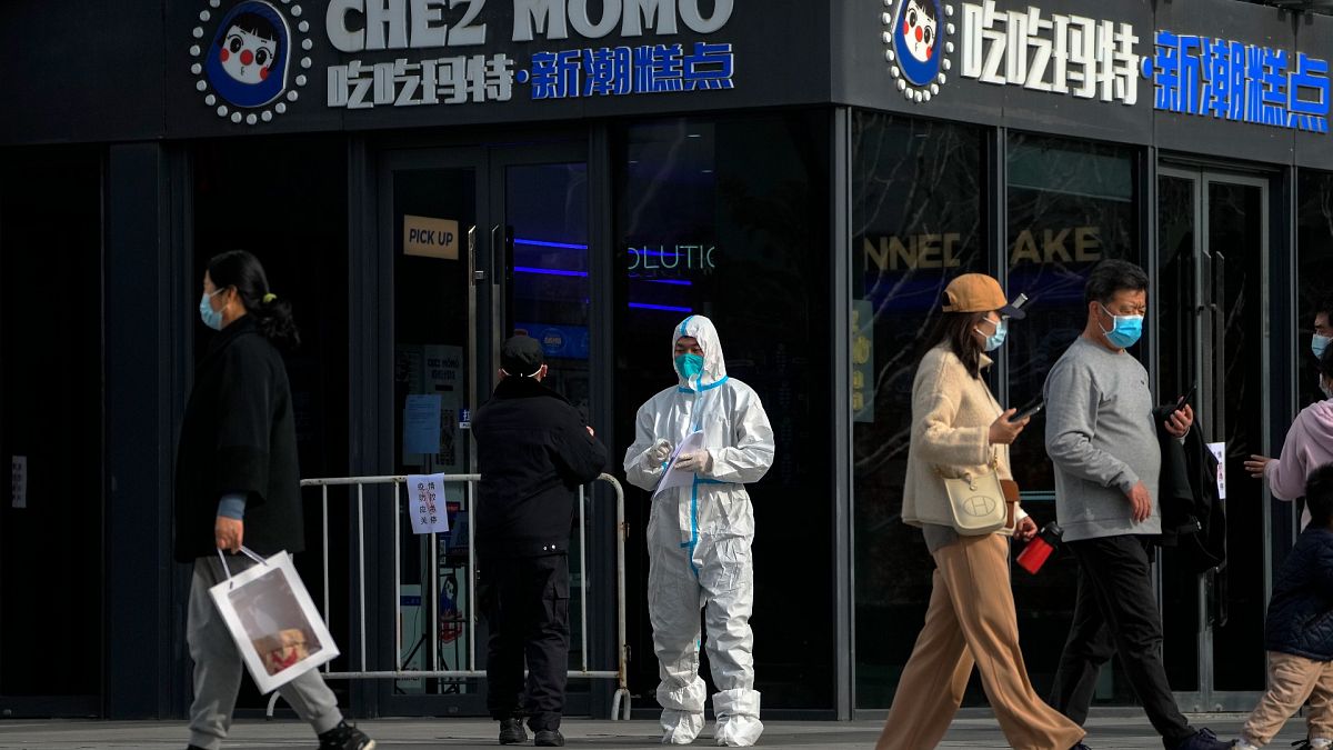عامل يرتدي بدلة واقية يضع إخطارات إغلاق في المطاعم في مبنى مكتب تجاري مغلق كجزء من ضوابط COVID-19 في بكين هذا الثلاثاء