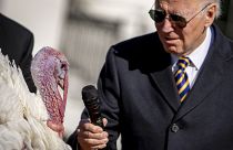 US President Joe Biden holds the microphone to 'Chocolate', the national Thanksgiving turkey, during a pardoning ceremony at the White House.