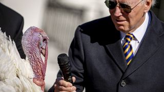 US President Joe Biden holds the microphone to 'Chocolate', the national Thanksgiving turkey, during a pardoning ceremony at the White House.