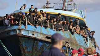 Migrants look out of a fishing boat docked at the port of Palaiochora in southeastern Crete, Greece, after its arrival, on Tuesday, Nov. 22, 2022.