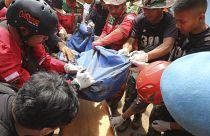 Rescuers remove the body of a victim recovered from under the rubble at a village hit by a landslide in Cianjur, West Java