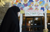 امرأة محجبة تمر من أمام لافتة لدعم الأسر الأفغانية" في مدرسة سانت أرميل في رين، غرب فرنسا، في 7 سبتمبر 2021.
