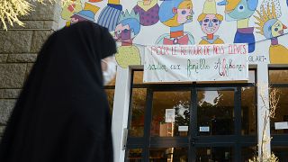 امرأة محجبة تمر من أمام لافتة لدعم الأسر الأفغانية" في مدرسة سانت أرميل في رين، غرب فرنسا، في 7 سبتمبر 2021.