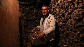 Gheorghe Batca carries firewood from a storage room to his house outside Chisinau, Moldova, Sunday, Oct. 16, 2022