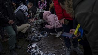 Жители Херсона заряжают мобильные телефоне у пункта подзарядки в центре города, 20 ноября 2022
