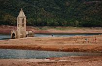 People walk arround the remains of the church of Sant Roma de Sau as it emerges from the low waters of the Sau Reservoir, north of Barcelona, Spain.