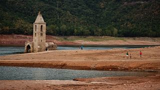 People walk arround the remains of the church of Sant Roma de Sau as it emerges from the low waters of the Sau Reservoir, north of Barcelona, Spain.