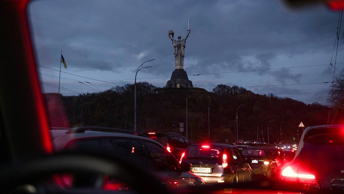 Cars move in the dark, with the Motherland Monument in the background, during a blackout in Kyiv, Ukraine, Friday, Nov. 11, 2022