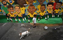 Uma criança joga futebol diante de uma imagem do "escrete" na favela Rocinha
