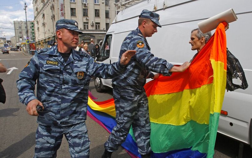 Des policiers russes arrêtent un militant des droits des homosexuels avec son drapeau lors d'une tentative d'organiser une gay pride à Moscou, Russie, le 27 mai 2012