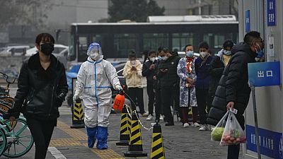 Работники в защитных костюмах устанавливают барьеры на улицах Пекина