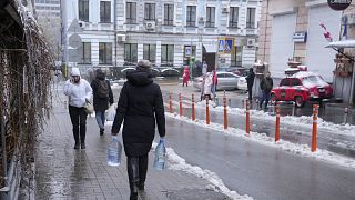 امرأة تعمل في مقر حكومي تابع لوزارة الصحة في كييف تنقل المياه صباح الخميس 24 نوفمبر