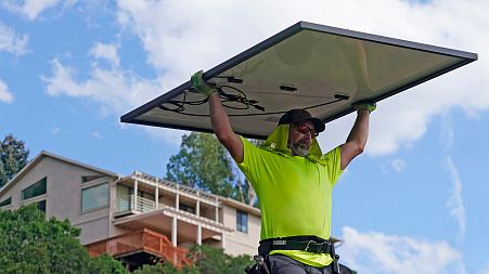 Phil Snow, of Power Shift Solar, installs a solar panel at a home in Salt Lake City.