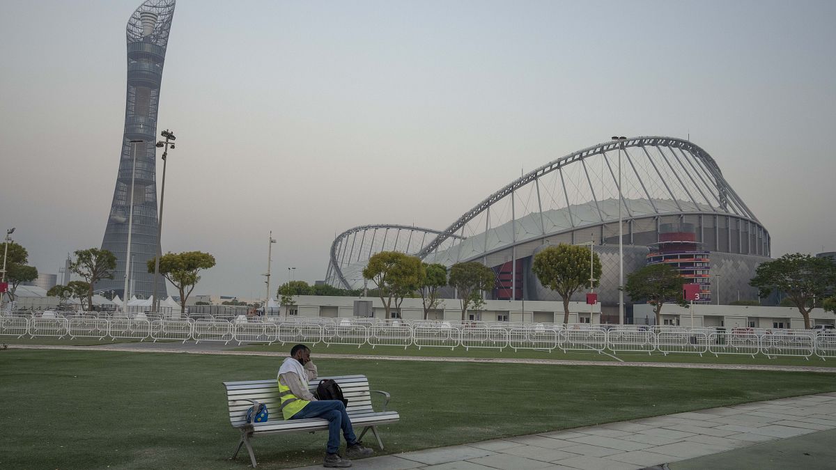 A migrant worker sleeps on a bench before his early morning shift, in front of Khalifa International Stadium in Doha, Qatar.