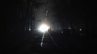 People cross the road at the city center which lost electrical power after a Russian rocket attack in Kyiv