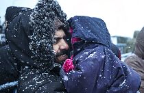 Ein Vater hält sein Kind, während er bei Schneefall vor einem Logistikzentrum am Kontrollpunkt "Kuznitsa" an der belarussisch-polnischen Grenze in der Nähe von Grodno, Belarus
