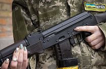An armed civil defence woman holds a Kalashnikov assault rifle while patrolling an empty street due to a curfew in Kyiv, 27 February 2022