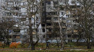 A woman walks past a recently damaged building due to a Russian strike in Kherson, southern Ukraine