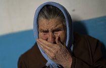 A ucraniana Lubov Oleinikova, 83 anos, chora dentro do seu edifício danificado, durante um ataque russo em Kherson.