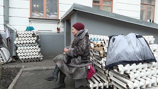 Vira Larina, a resident of Bohorodychne, sits near the monastery 