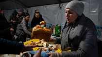 A volunteer gives a free meal to people who lost power after a recent Russian rocket attack on a heating point in Vyshhorod, north of Kyiv, Ukraine, Friday, Nov. 25, 2022.