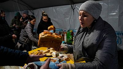 A volunteer gives a free meal to people who lost power after a recent Russian rocket attack on a heating point in Vyshhorod, north of Kyiv, Ukraine, Friday, Nov. 25, 2022.