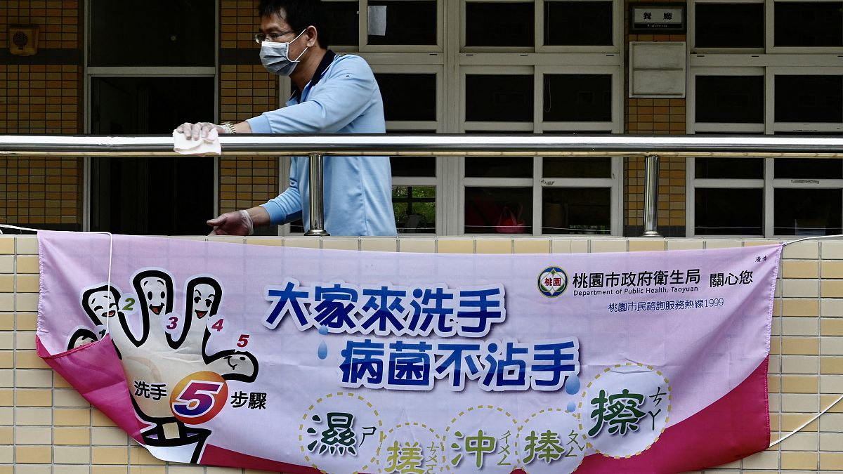 رجل يقف خلف لافتة تخبر الطلاب بكيفية غسل أيديهم للوقاية من فيروس كورونا في مدرسة إعدادية في تاويوان. 2020/02/29