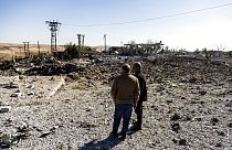 People look at a site damaged by Turkish airstrikes that hit an electricity station in the village of Taql Baql, in Hasakeh province, Syria