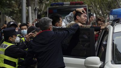 Kínai tüntetőt tuszkolnak egy járőrautóba Sanghajban