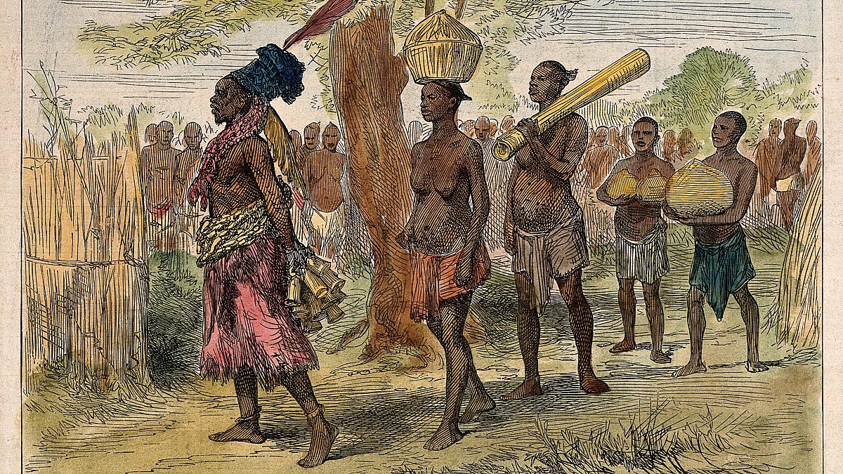 A Mrua medicine man or shaman with his assistants, Central Africa. Coloured wood engraving after V.L. Cameron.