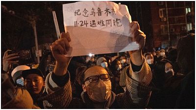 A protester holds up a sign which reads "Commemorate Urumqi Nov 24 compatriots who died" in Beijing.