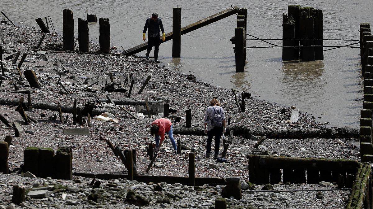 People mudlark on the banks of the River Thames looking for historic artefacts, coins, clay pipes or Roman pottery, in London