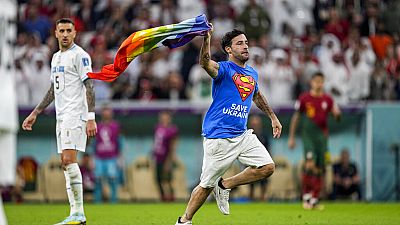 A pitch invader runs across the field with a rainbow flag during the World Cup match between Portugal and Uruguay, at the Lusail Stadium in Lusail, Qatar, 28 October.