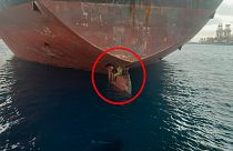 The migrants are pictured on the rudder of the ship