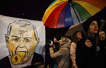  Protesters take photos of a poster depicting the leader of Poland's Law and Justice party, Jaroslaw Kaczynski, on Monday.