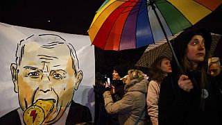  Protesters take photos of a poster depicting the leader of Poland's Law and Justice party, Jaroslaw Kaczynski, on Monday.