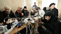 Des habitants de Kherson rechargent leur téléphone à la gare de la ville, l'un des rares bâtiments à disposer de l'électricité.