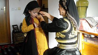 Μητέρα ετοιμάζει την κόρη με την παραδοσιακή φορεσιά για τον Τρανό χορό