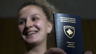 Kosovo Albanian woman Teuta Begolli shows her new passport after it was presented by Kosovo's Prime Minister Hashim Thaci