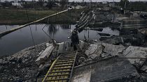 Una mujer camina por un puente explotado en Bajmut, Ucrania, región de Donetsk, Ucrania, el viernes 11 de noviembre de 2022.