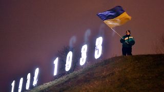 Украинский флаг на фоне инсталляции в память о жертвах Голодомора в Украине