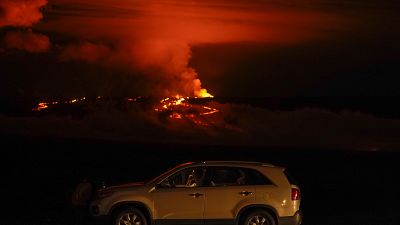 Un hombre habla por teléfono en su coche junto a Saddle Road mientras el volcán Mauna Loa entra en erupción el miércoles 30 de noviembre de 2022, cerca de Hilo, Hawái.
