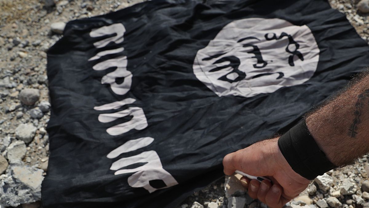 علم داعش قبل حرقه في الرقة شمال شرق سوريا.