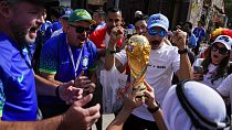 Soccer fans cheer as a man hoists a replica of the World Cup trophy at the Souq Waqif, in Doha, Nov. 23, 2022.