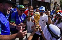 Soccer fans cheer as a man hoists a replica of the World Cup trophy at the Souq Waqif, in Doha, Nov. 23, 2022.